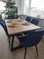 Stół Loft Trapez z drewnianym blatem i czarnymi metalowymi nogami w nowoczesnej jadalni. Zdjęcie aranżacyjne stołu z granatowymi krzesłami pokazujące wygląd i proporcje mebla we wnętrzu.